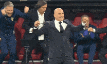 a man in a suit and tie stands in a crowd of men