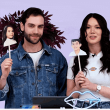 a man in a denim jacket and a woman in a white shirt with the word dickies on it holding a picture of a boy
