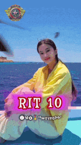 a woman in a yellow jacket sits on a boat in front of the ocean with rit 10 written on the bottom