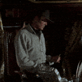 a man in a hat smoking a cigar in a dark room