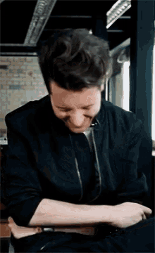a man in a black jacket is holding another man 's arm and laughing .