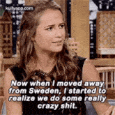a woman is sitting on a couch and talking to someone while wearing a black dress .