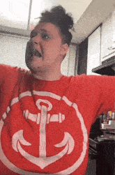 a man wearing a red shirt with an anchor on it .