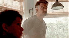 a man and a woman are standing in front of a window in a kitchen .