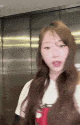 a woman with long brown hair is standing in front of a mirror