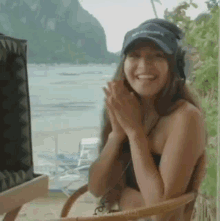 a woman in a bikini is sitting in a chair with her hands folded .