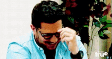a man wearing glasses and a watch is covering his face with his hand
