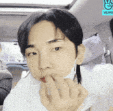 a man wearing a face mask is sitting in a car with vlive written on the roof