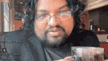 a man with glasses and a beard holds a glass
