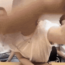 a woman in a white shirt is sitting at a table with her arms outstretched .