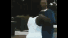 a man in a white shirt and a man in a blue shirt are standing next to each other .