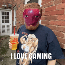 a man wearing a mask and a shirt that says i love gaming is holding a drink