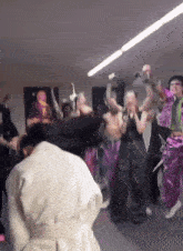 a group of people are dancing in a room with a picture of a man in the background