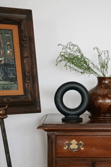 a framed painting of a man sitting at a table next to a vase with flowers in it