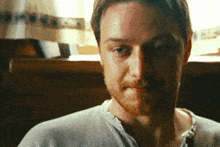 a man with a beard wearing a white shirt looks at the camera