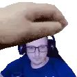 a man wearing glasses and headphones is being slapped on the head by a large hand .