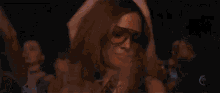 a woman wearing orange sunglasses is dancing in a crowd of people at a party .