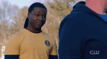 a man wearing a yellow shirt with the letter s on it stands next to another man