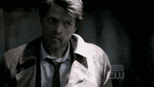 a man in a suit and tie is standing in a dark room with blood on his face .