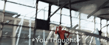 a man is hanging from a ceiling in a building with the words `` you thought '' below him .