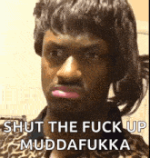 a man in a leopard print shirt is making a funny face and saying `` shut the fuck up muddafukka '' .