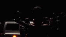 a woman wearing sunglasses stands in front of a crowd of people taking pictures