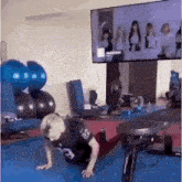 a woman is doing push ups in a gym while watching a tv .