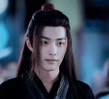 a young man with long hair is wearing a black shirt and a red flower in his hair .