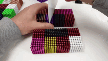 a person is playing with a stack of colorful magnet beads