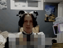 a man wearing a cat ear headset looks at the camera in a bedroom