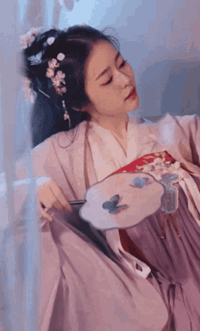 a woman in a purple dress is holding a fan in her hand .