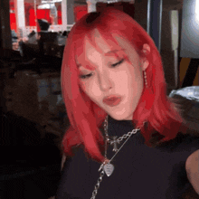 a girl with red hair is wearing a black shirt and a necklace with a heart on it .