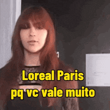 a woman with red hair is standing in front of a sign that says loreal paris