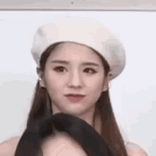 a close up of a woman wearing a beret and a black tie .