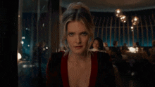 a woman in a red dress is sitting at a table in a restaurant and looking at the camera .