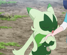 a person is petting a green cartoon character