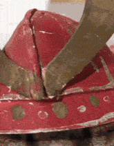 a close up of a red and gold helmet with a gold horn