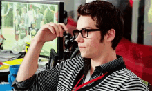 a man wearing glasses and a striped shirt is sitting in front of a computer