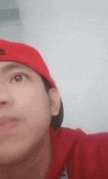 a close up of a man wearing a red hat and a red hoodie .