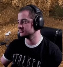 a man wearing headphones and a black shirt is sitting in a chair in a field .