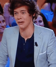 a man in a suit is making a funny face while standing in front of a crowd of people .