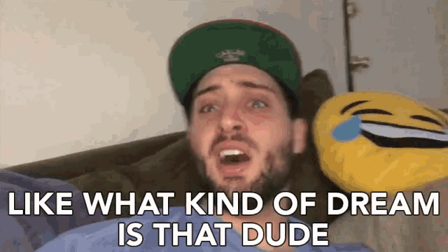 a man is laying on a couch with a laughing emoji pillow and the words like what kind of dream is that