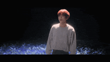 a man with red hair is standing in front of a field of blue flowers