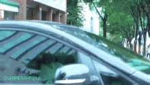 a car is parked on the side of the road in front of a building with trees in the background .