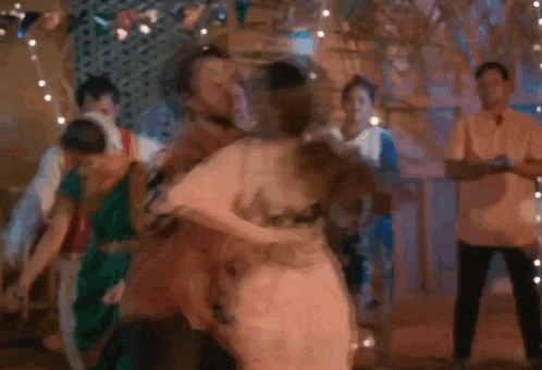 a man is holding a woman in his arms while dancing in front of a group of people .