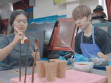 a man and a woman are sitting at a table with spoons