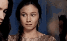 a woman is making a funny face while standing next to another woman in a room .