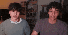 two young men are standing next to each other in a living room .
