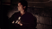 a man in a black shirt holds a bottle in his hand