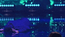 a man in a suit is dancing on a stage with a green background .